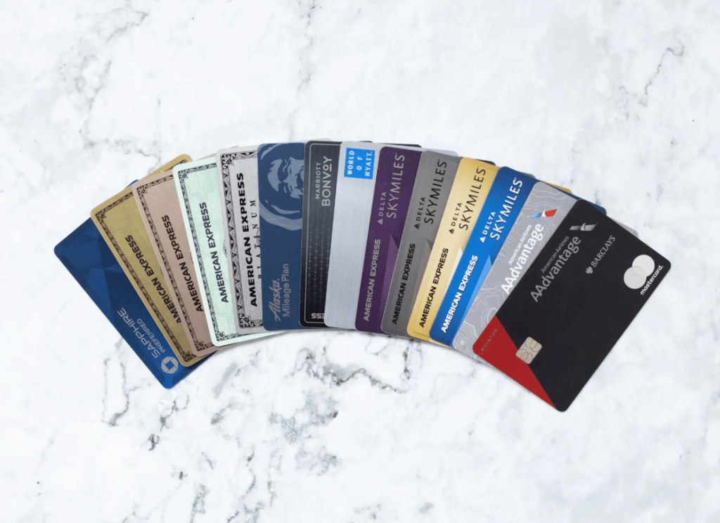 A fan of travel rewards credit cards spread out on a white marble surface, including Chase Sapphire Preferred, American Express, World of Hyatt, Delta SkyMiles, and AAdvantage cards.